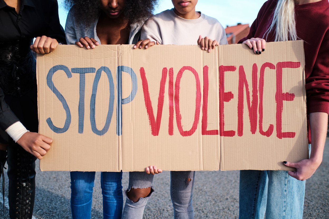 Cropped view of unrecognizable women holding a large placard protesting against gender violence.